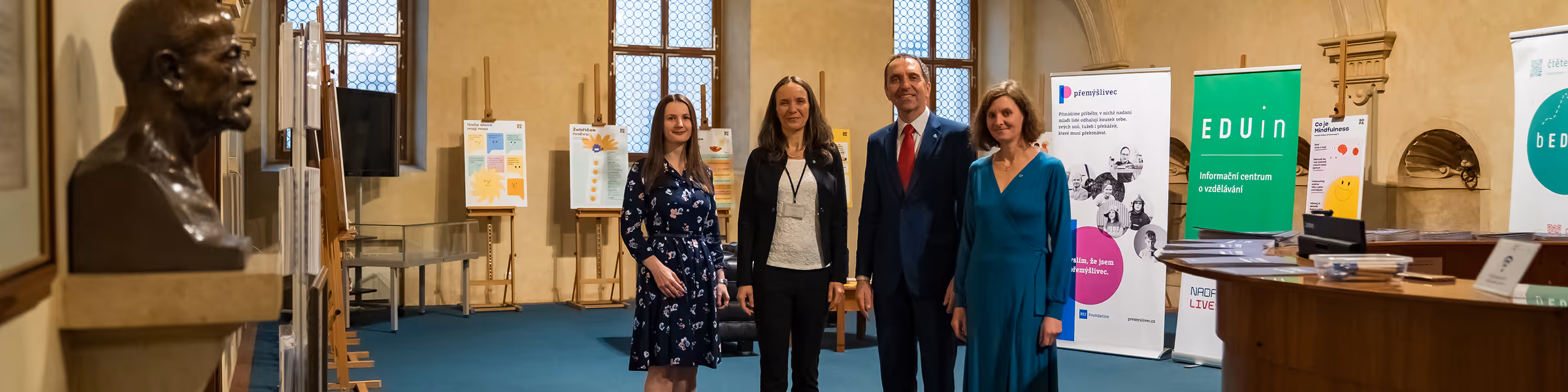 Group of people standing in an exhibition space with educational posters and banners.