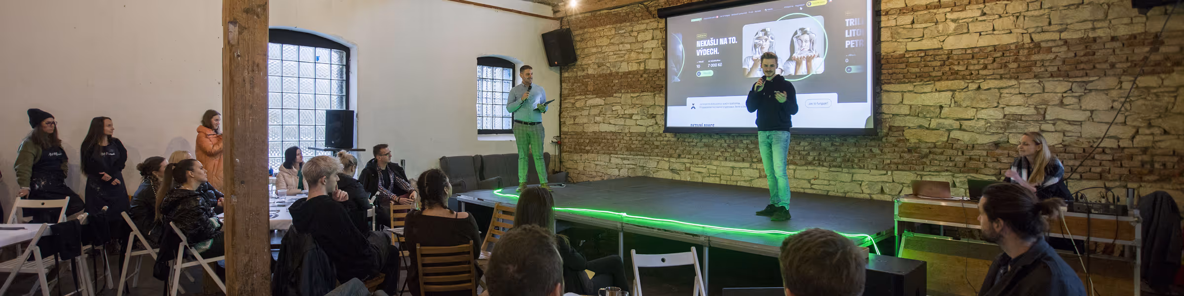 Speakers presenting on a stage in front of an audience at an indoor event.