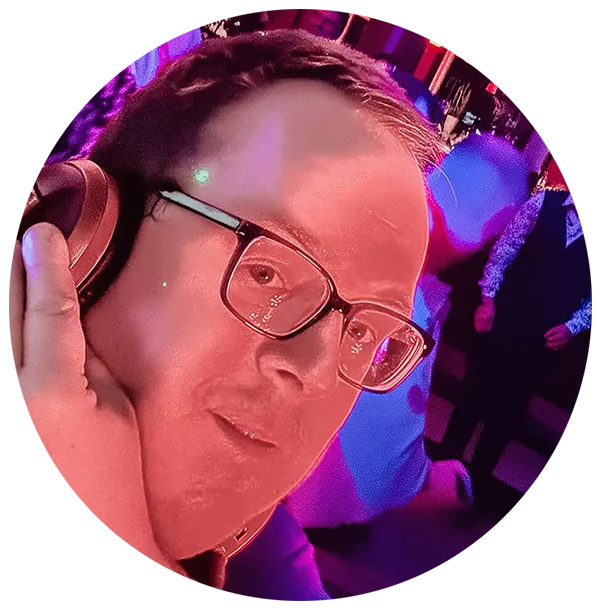 Im Vordergrund ist ein DJ mit Brille und Kopfhörern zu sehen, der von rosa und lila Lichtern angestrahlt wird, während im Hintergrund Menschen tanzen und sich in einer lebhaften, farbenfrohen Partykulisse unterhalten.
