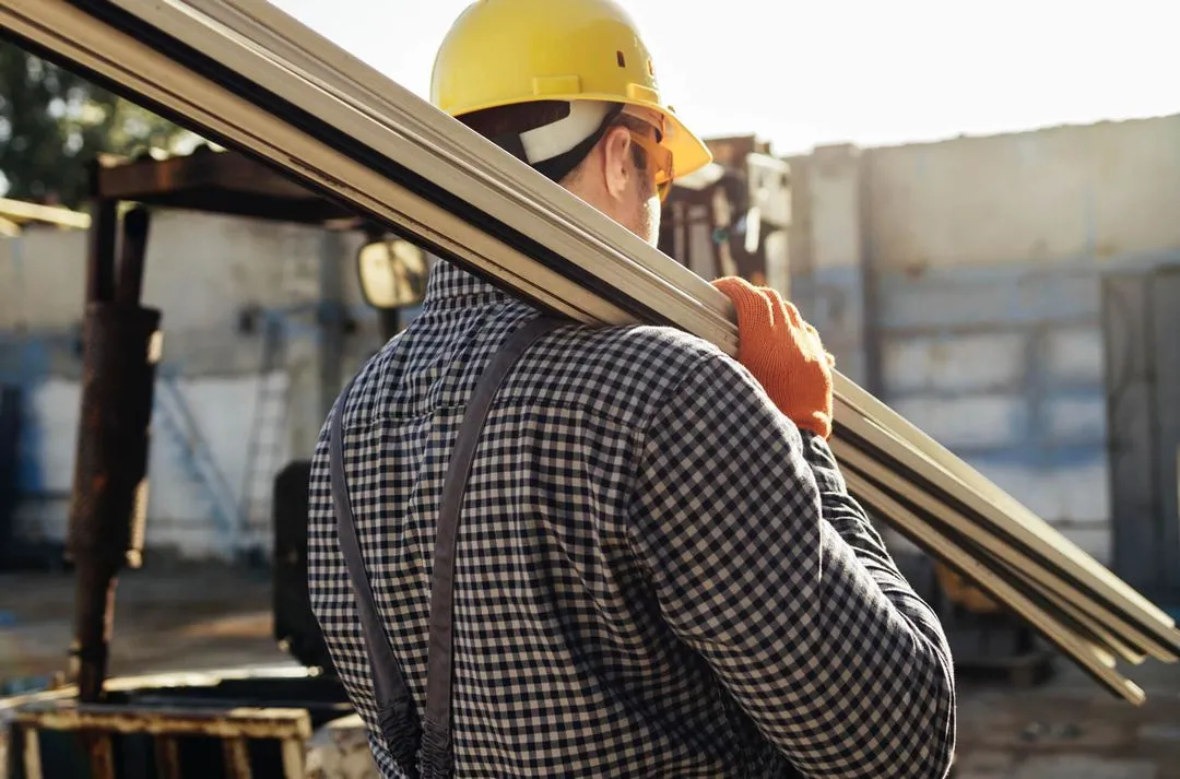 A Roof Tek employee carries metal beams for the future roof structure.