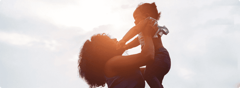 Mother lifting up baby outside
