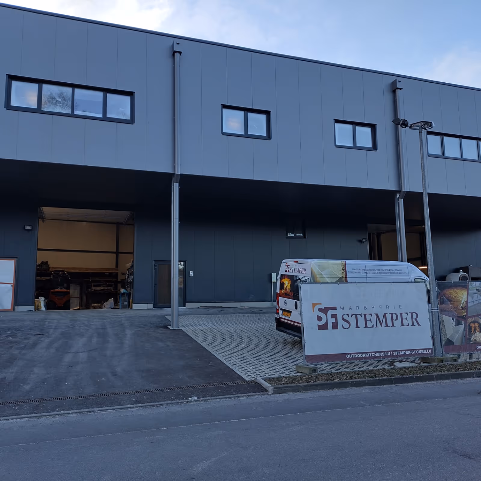 Façade de l'atelier Marbrerie Stemper avec fourgon et enseigne.