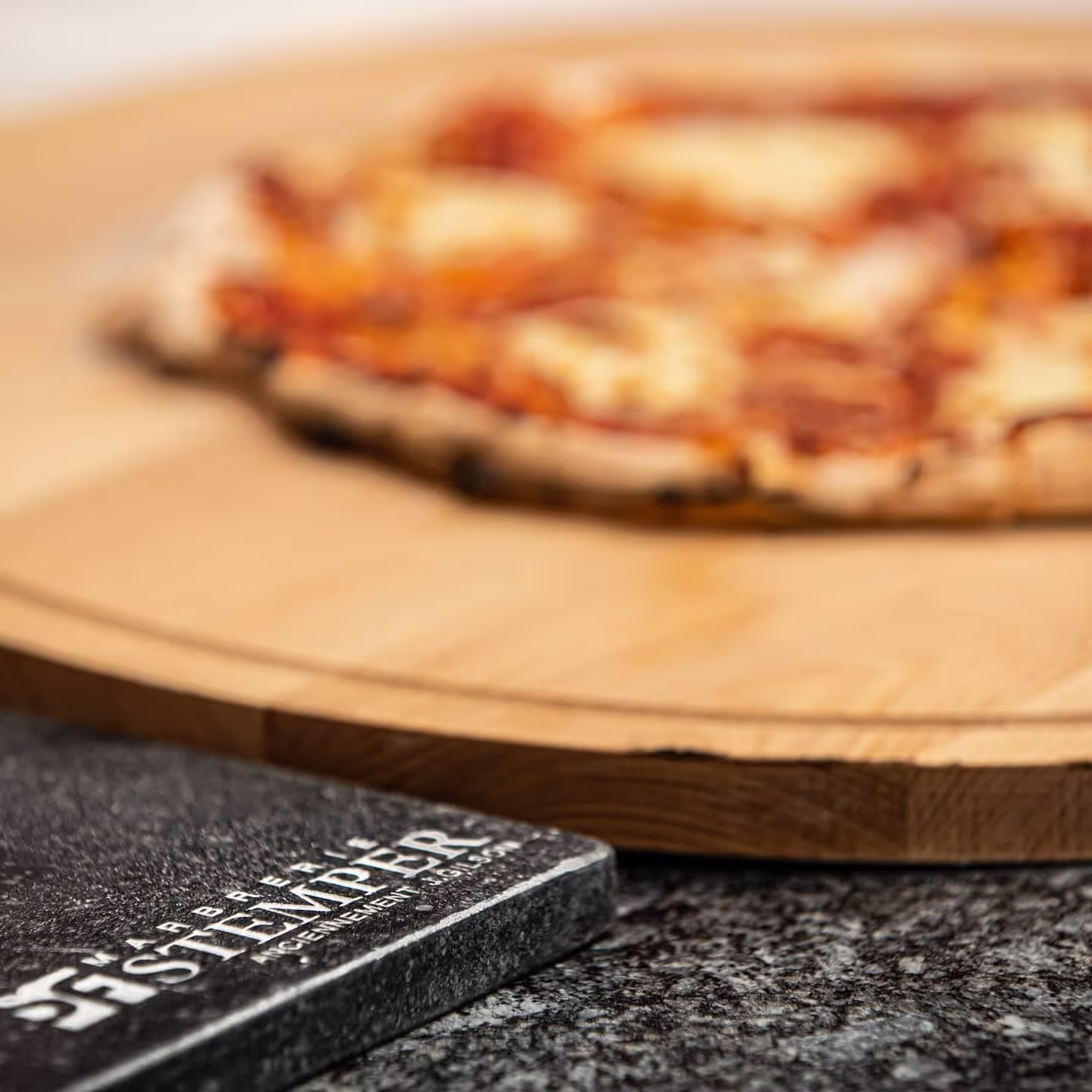 Stone plate with Stemper Stones engraved next to a board with a pizza