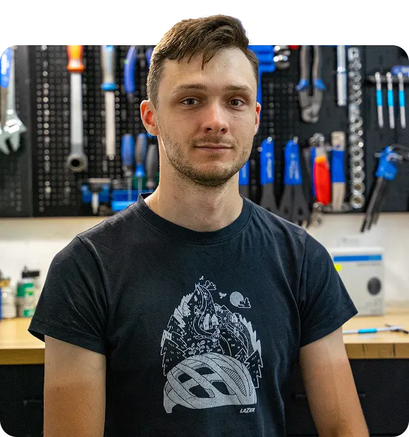 Właściciel Baginski Rowery w Łomży, stojący w warsztacie rowerowym na tle ściany z narzędziami.