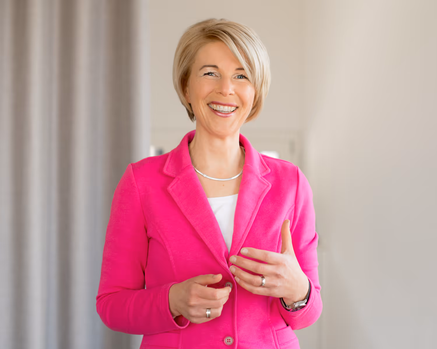Manuela Ederer strahlt in pinkem Blazer – voller Energie, Lebensfreude und Begeisterung für authentisches Verkaufen.