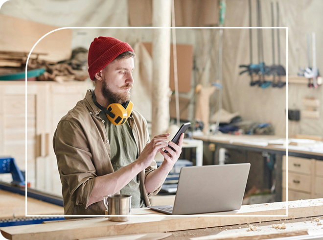 Trader sending an invoice from his mobile device whilst in his workshop