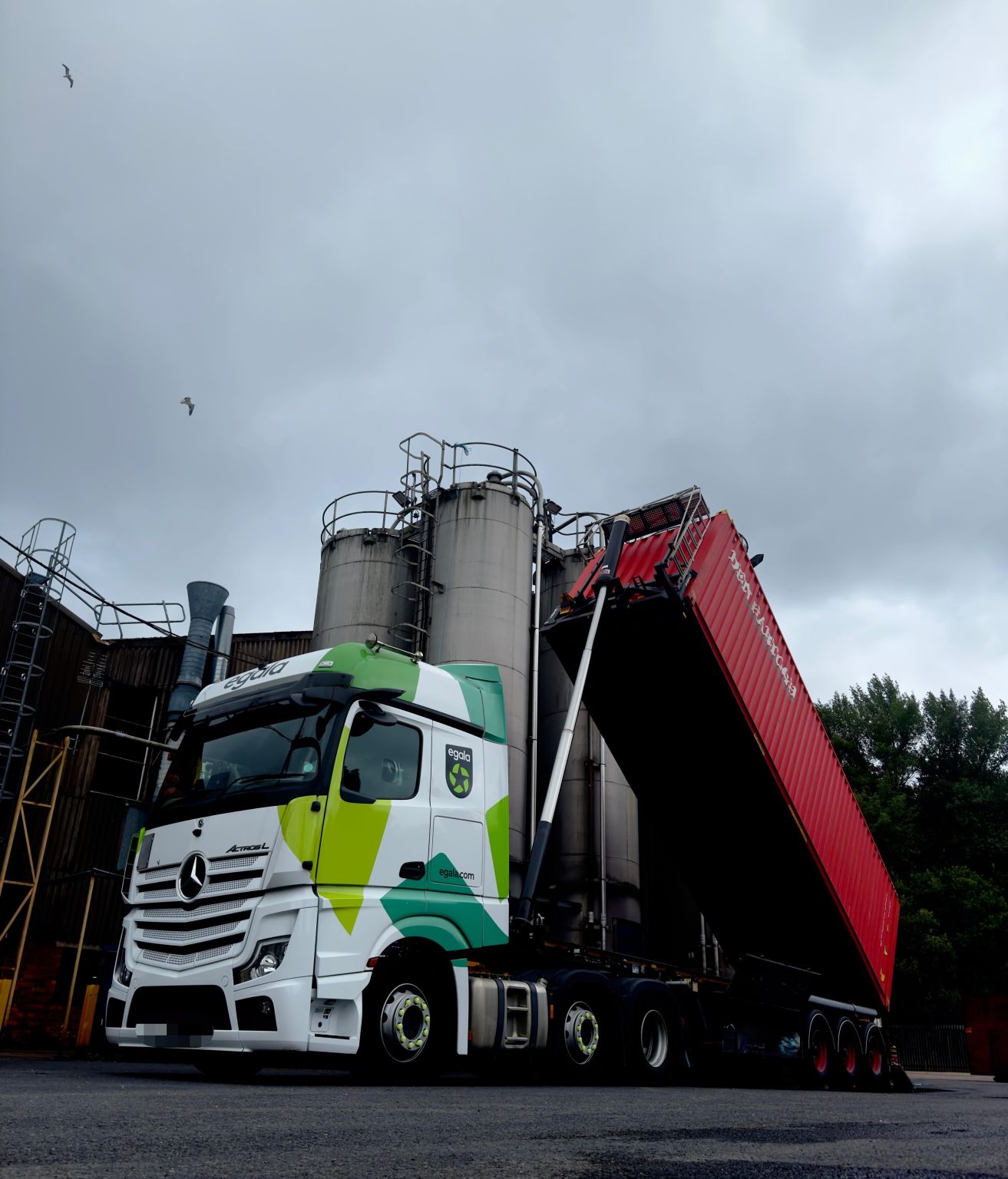 Egala by Boekestijn truck with a raised red trailer unloading materials at an industrial site.
