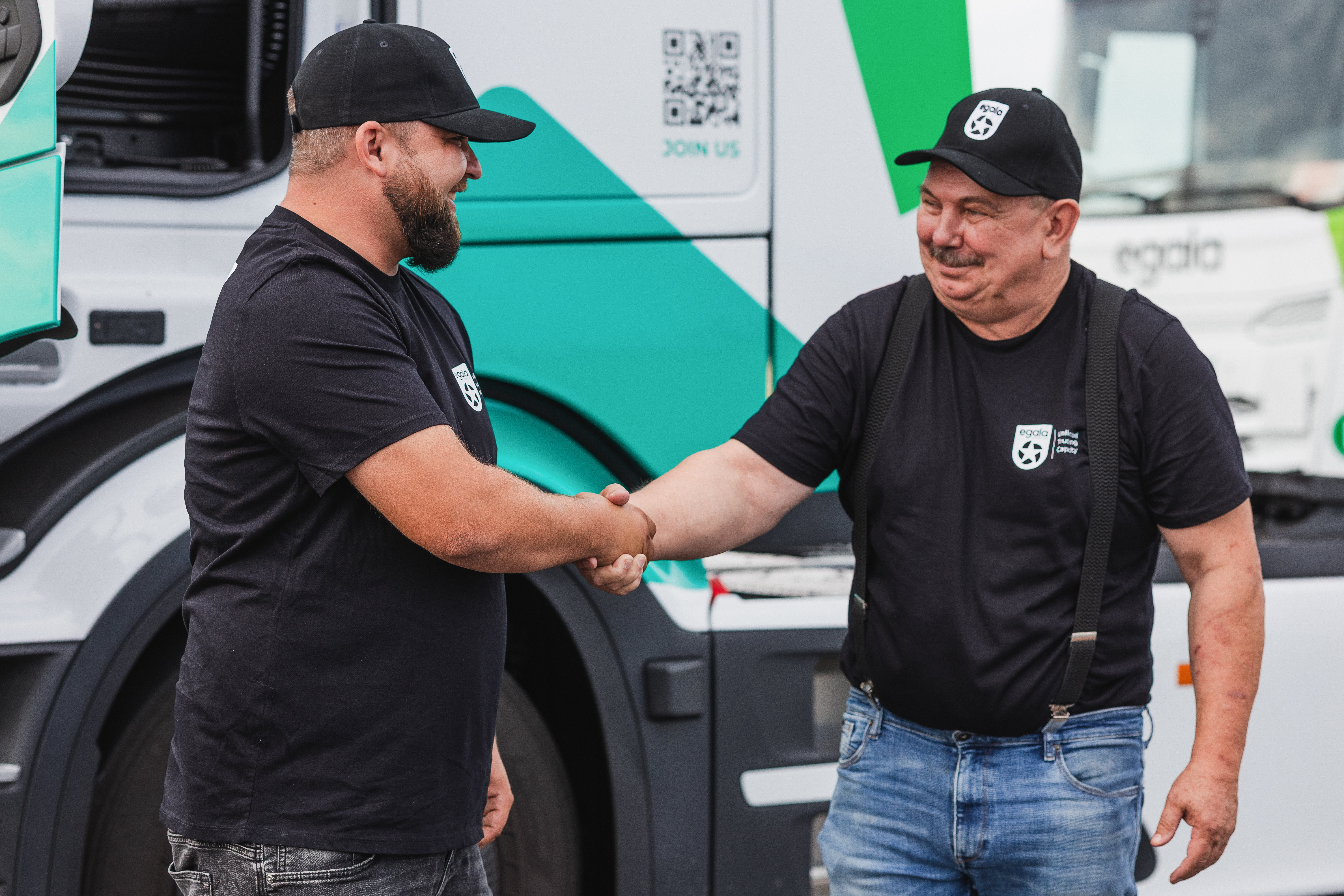 Two Egala by Boekestijn team members shaking hands in front of a modern green and white truck.