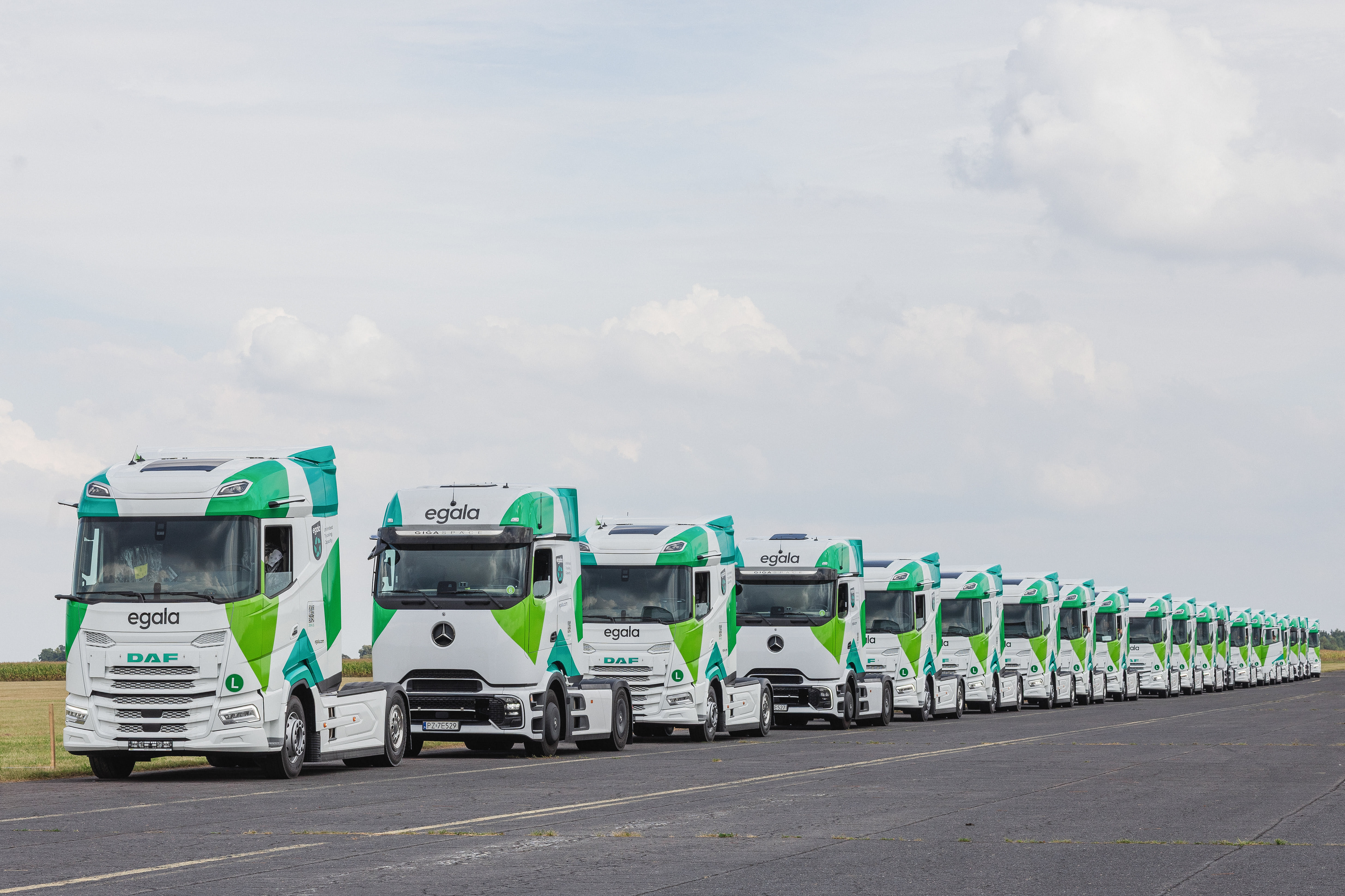 Row of Egala by Boekestijn green and white trucks parked in formation on an open lot.