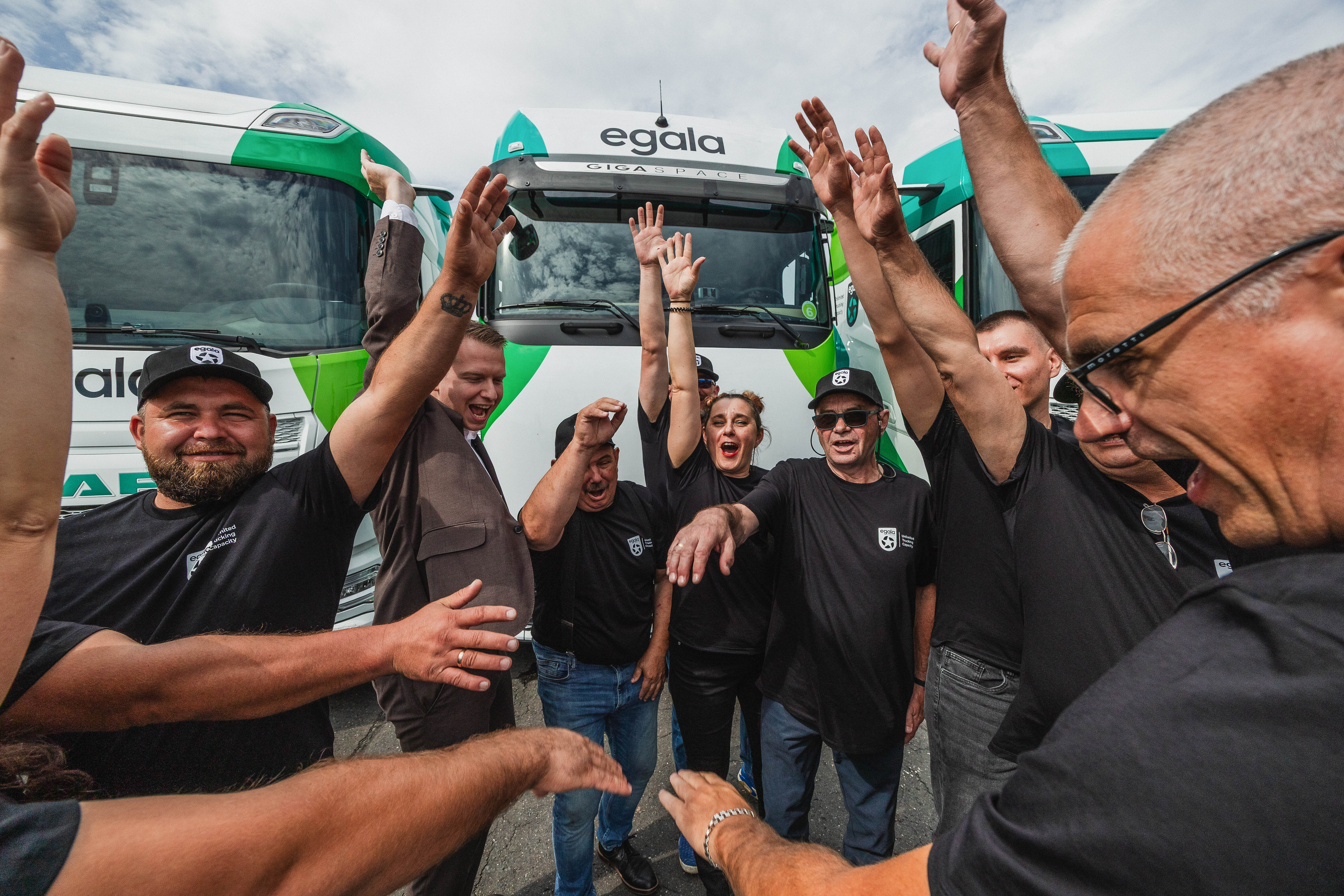 Egala by Boekestijn drivers celebrating together with raised hands in front of company trucks.