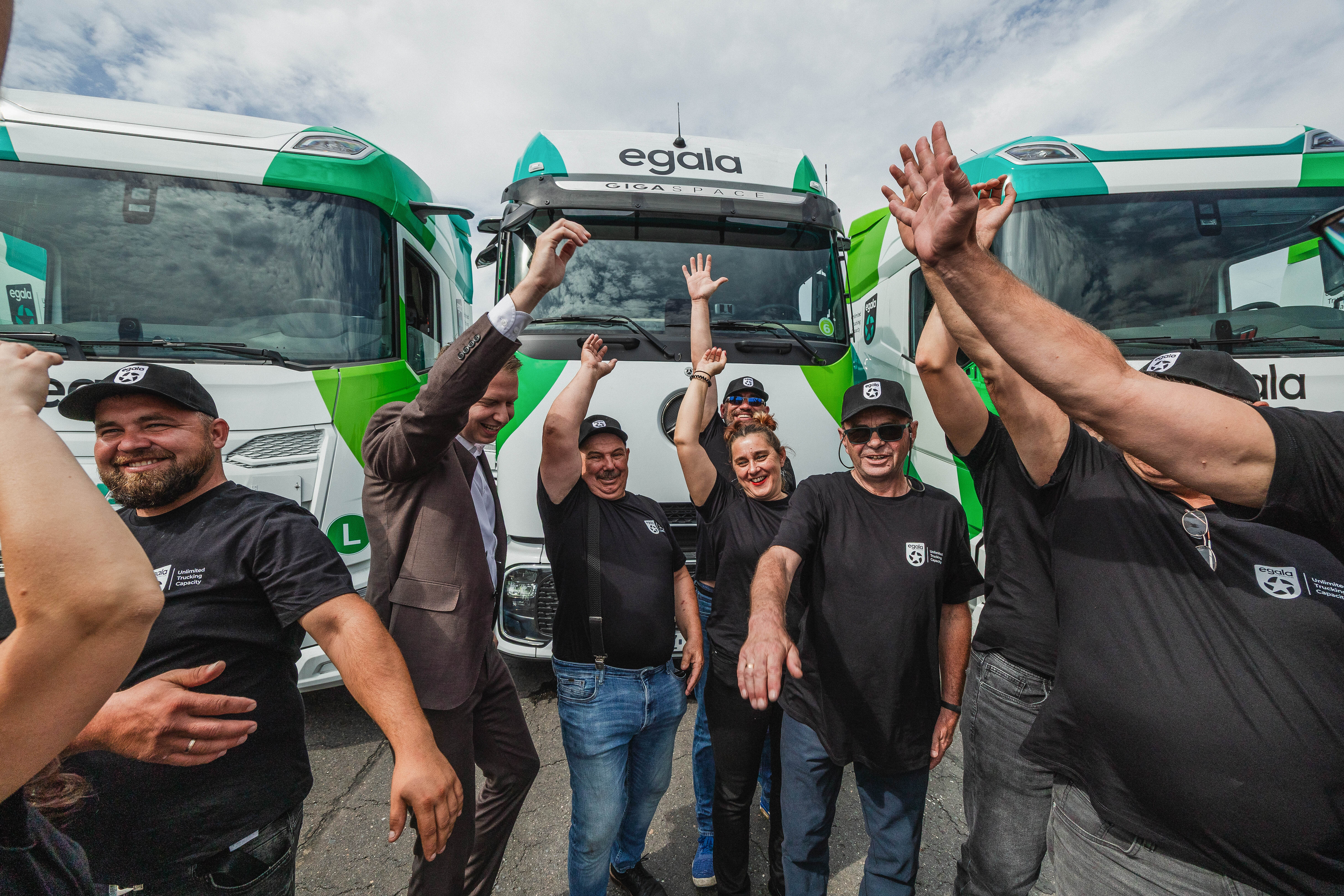 Egala by Boekestijn green and white trucks with team members raising their hands in celebration. Symbolizes teamwork, innovation, and integrated logistics solutions powered by Egala technology.