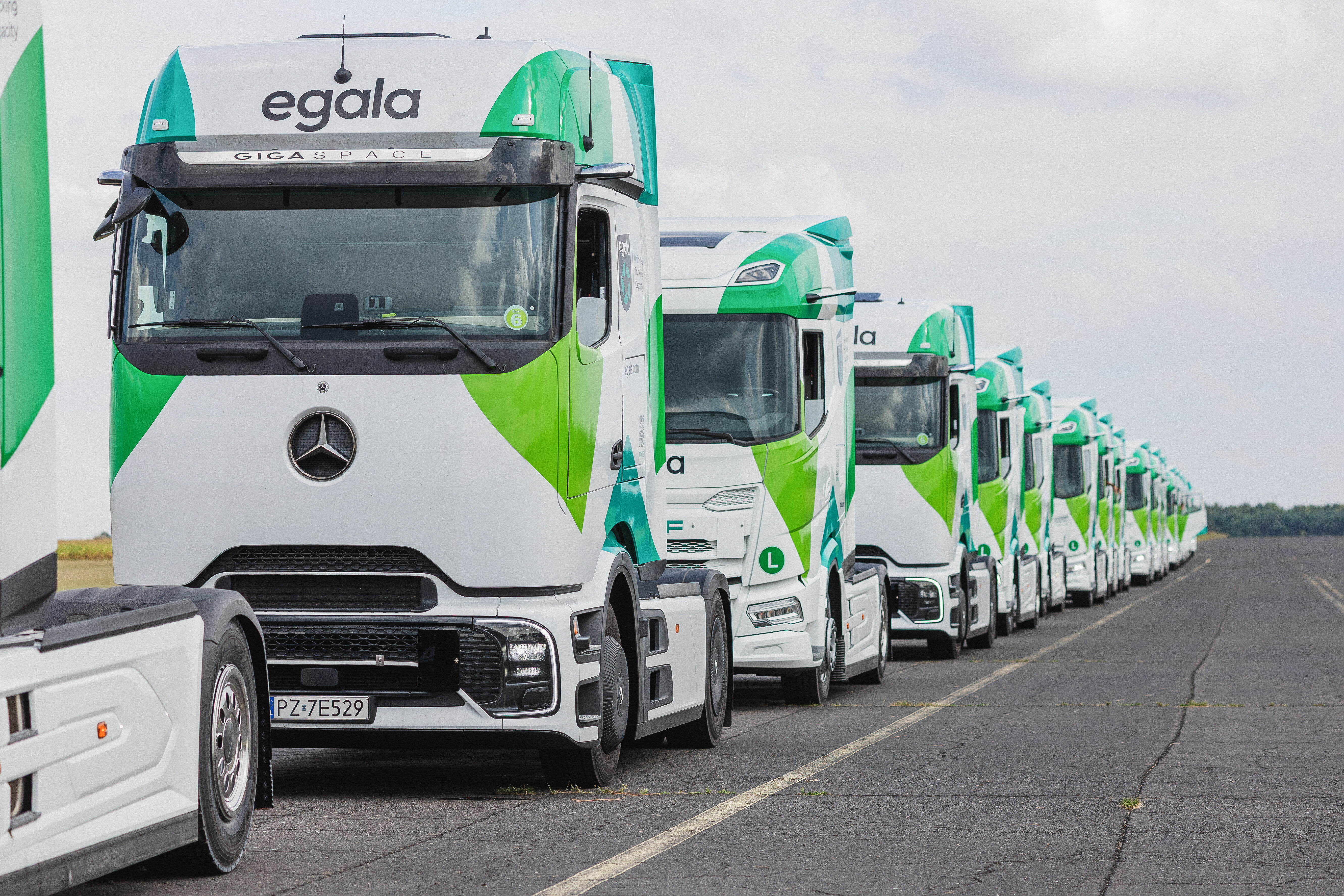 Line of Egala by Boekestijn trucks in green and white livery parked along a road.