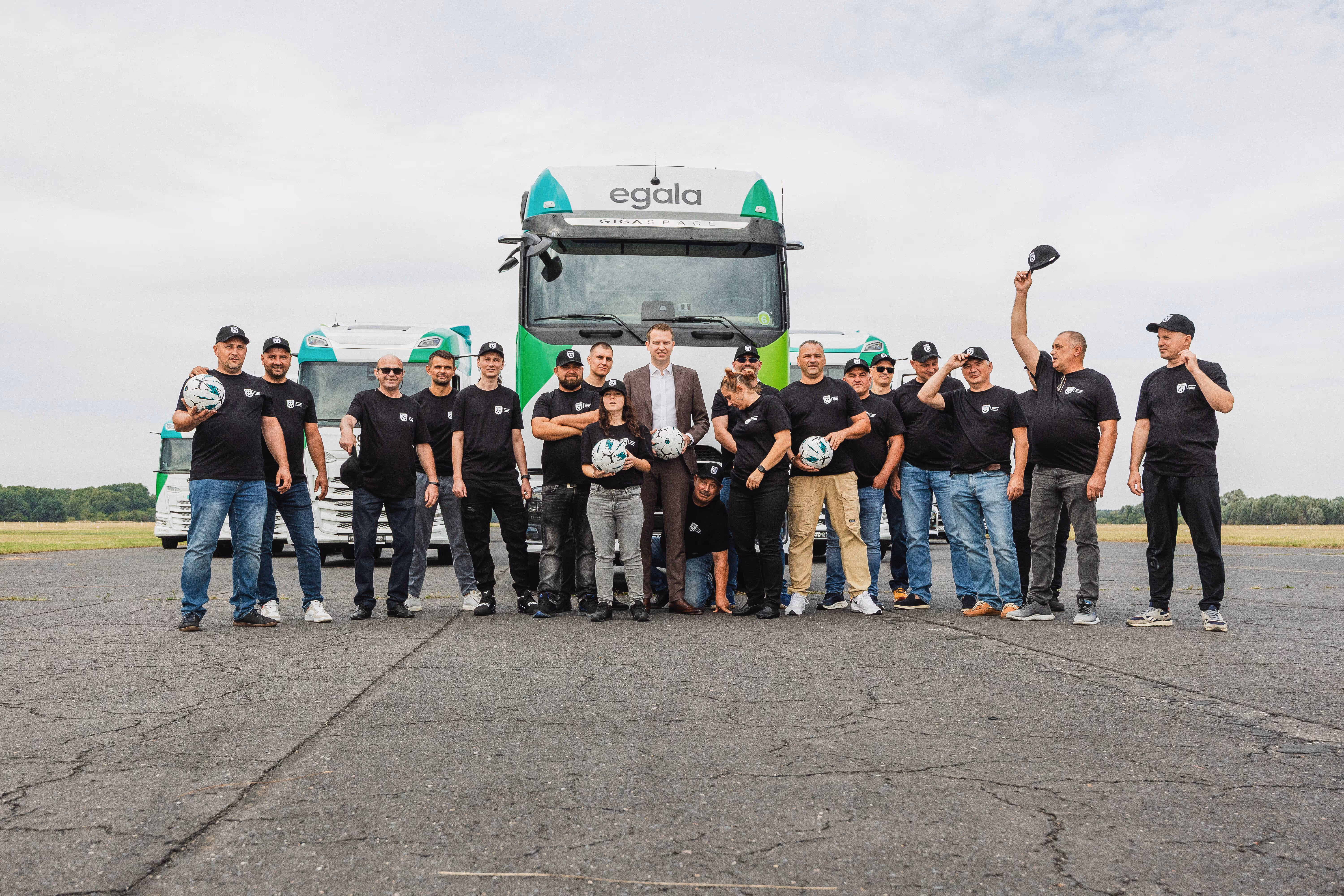 Egala by Boekestijn team standing in front of green and white trucks, celebrating together on an open road. Symbolizes teamwork, innovation, and the people driving modern, sustainable logistics