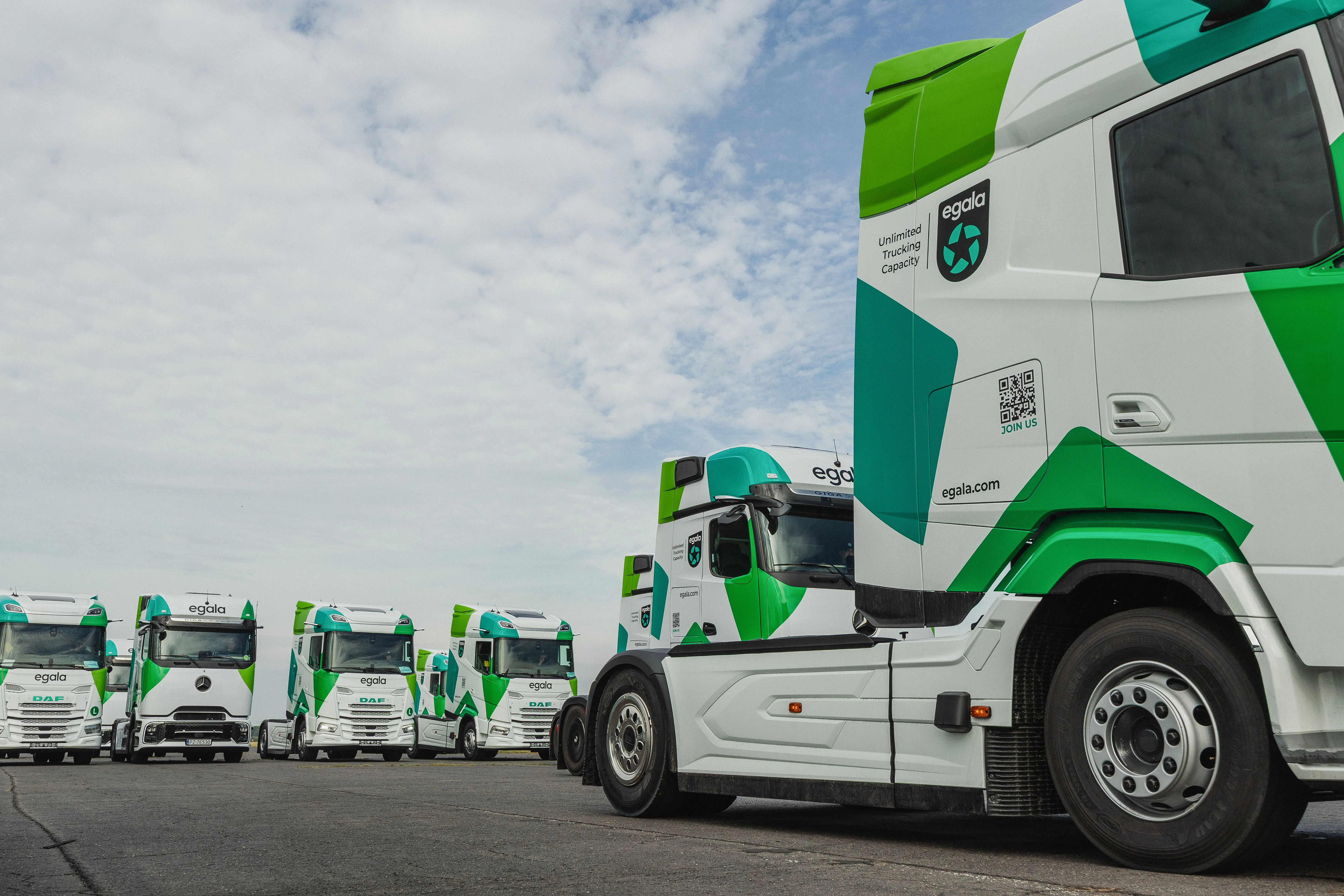 Egala by Boekestijn trucks lined up on a lot, with a close-up view of one green and white cab in the foreground.