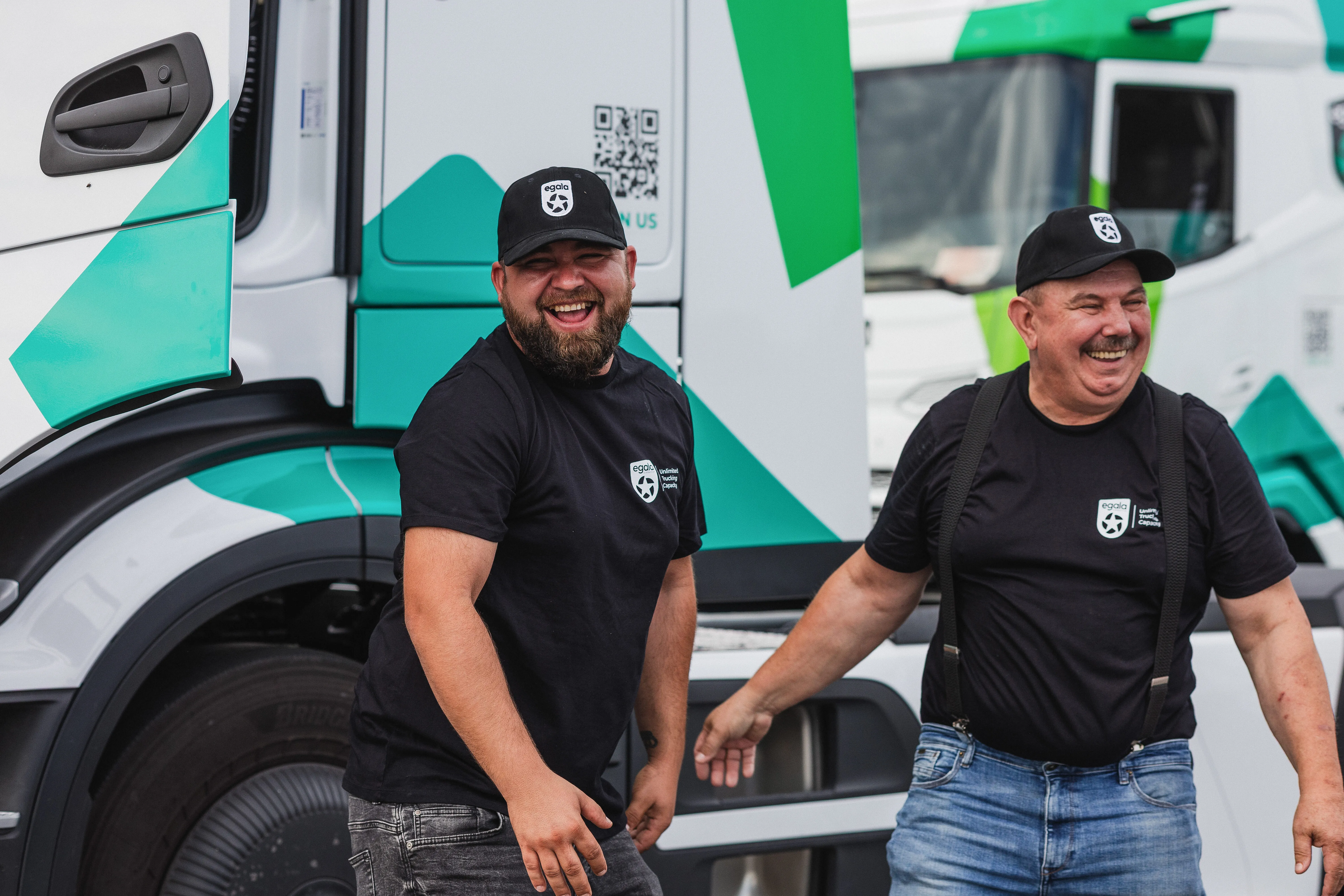 Egala by Boekestijn truck drivers smiling in front of green and white DAF trucks — representing teamwork, professionalism, and a positive driver culture in sustainable logistics