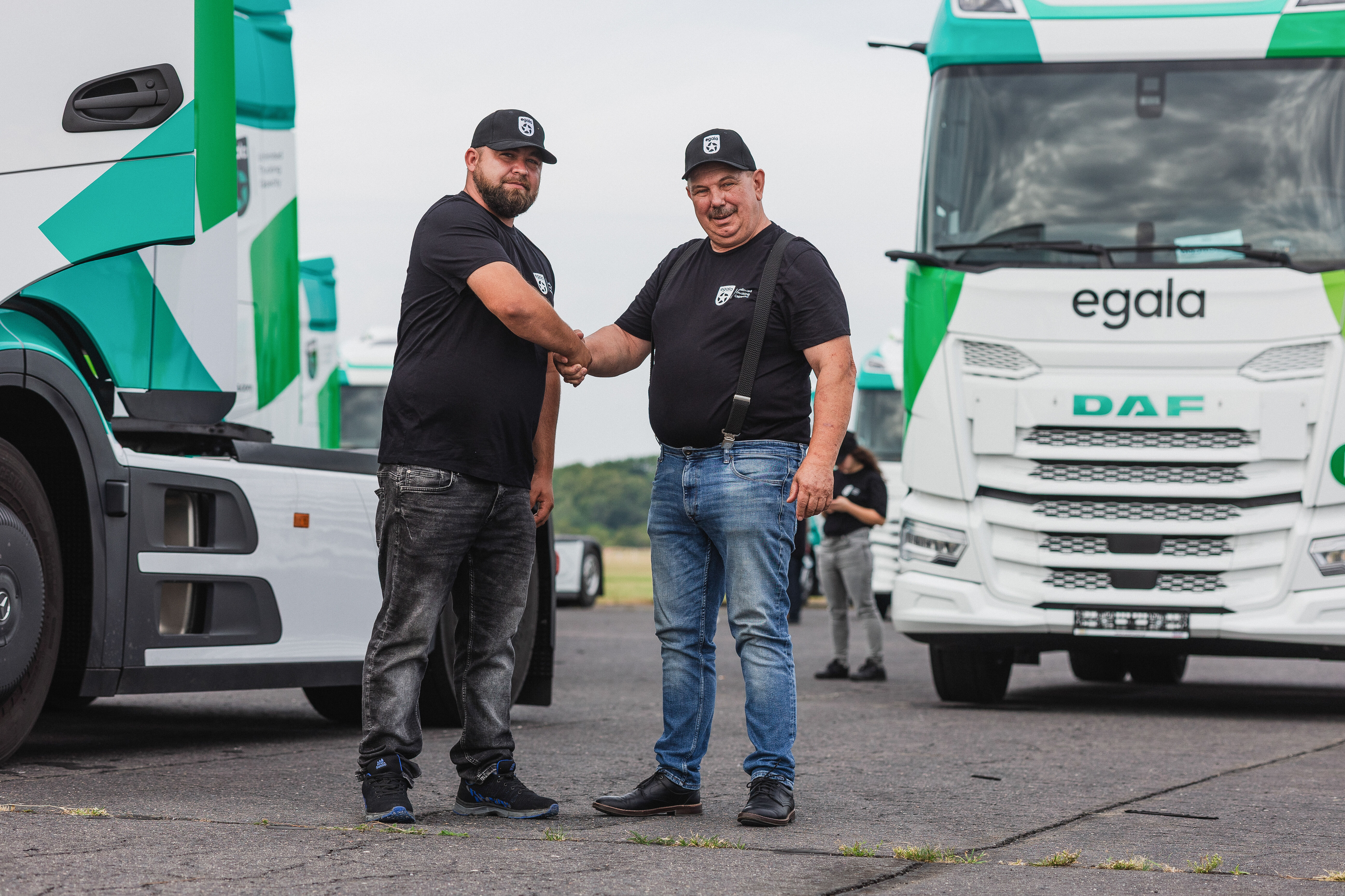 Two Egala by Boekestijn drivers shaking hands in front of eco-friendly trucks, representing teamwork, trust, and sustainable logistics across Europe
