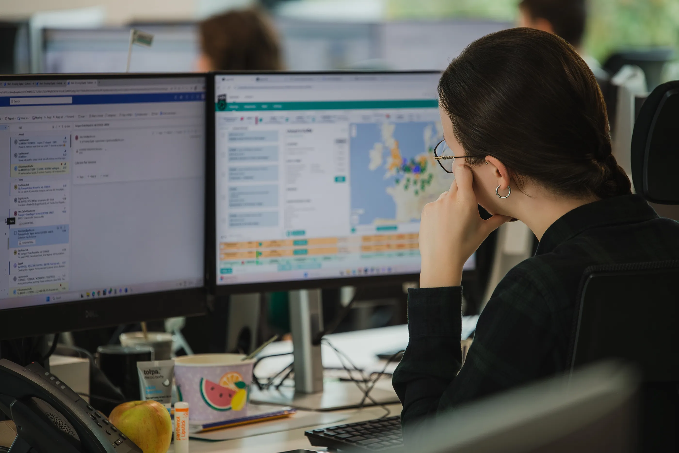 Logistics specialist at Egala by Boekestijn working at a dual-monitor workstation, analyzing European transport routes and shipment data on screen inside a modern operations office.