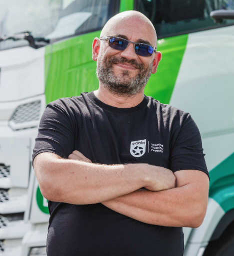 Egala truck driver standing confidently by the fleet — reflecting strength through diversity.
