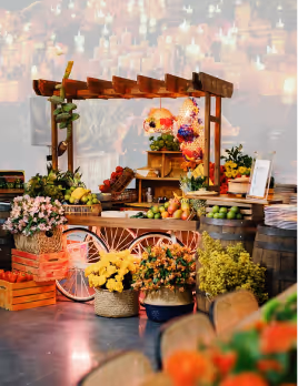 Decorative wooden cart decorated with flowers, fruits, and vegetables at an indoor event.