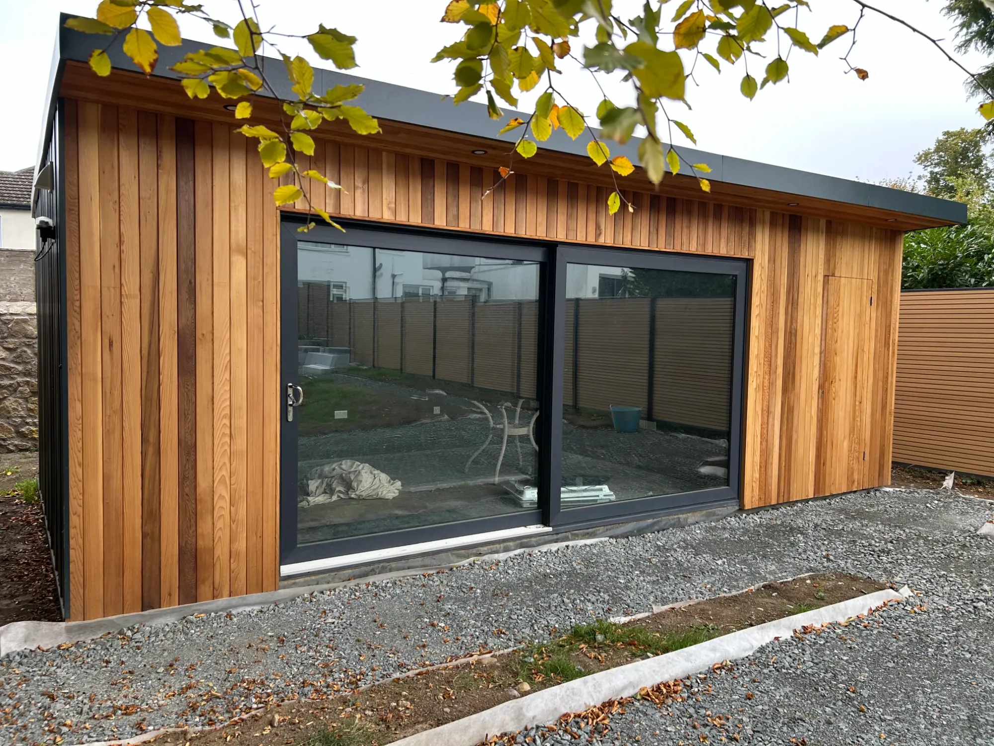 Timber-clad garden room with dark-framed sliding glass doors and a flat roof