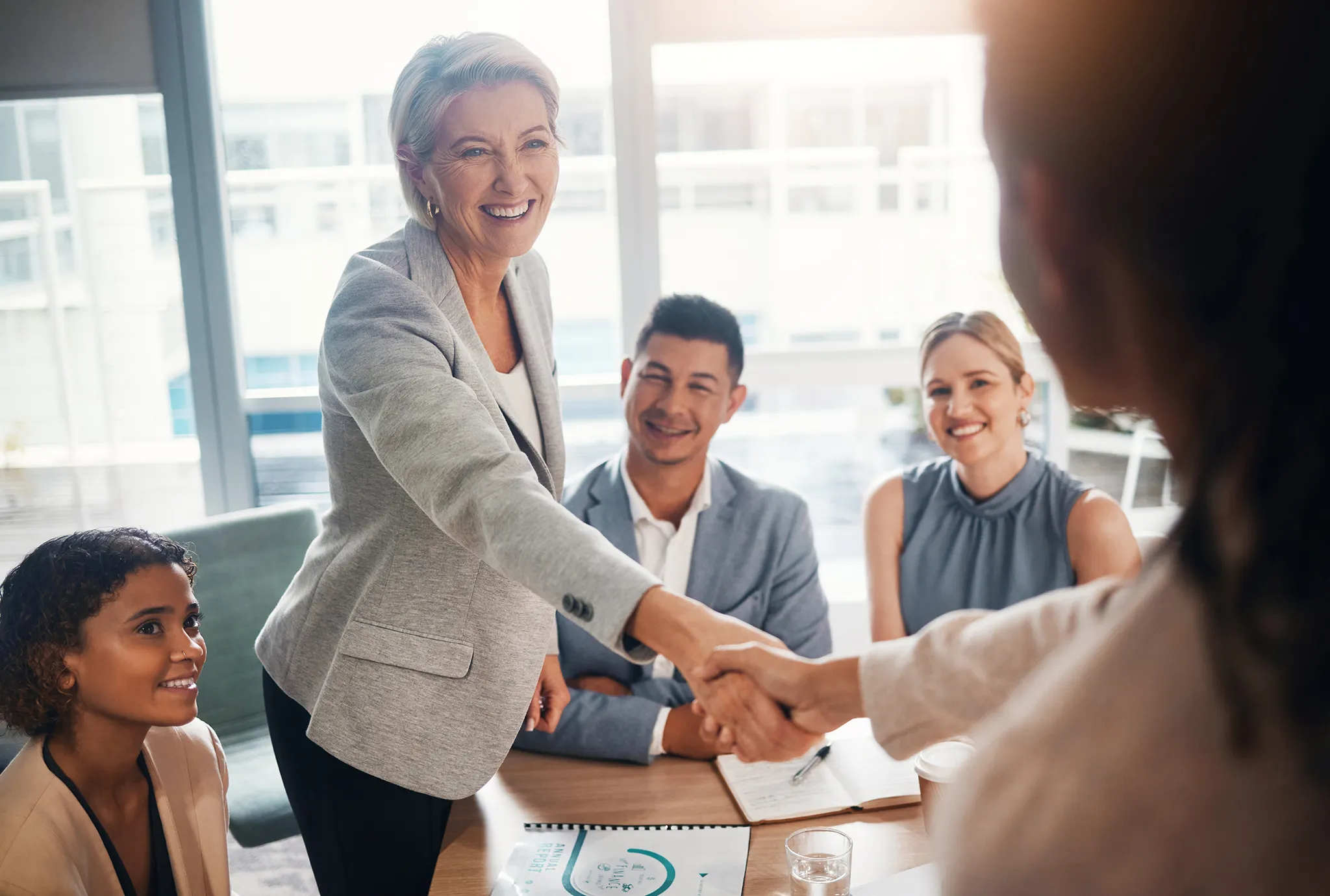 Businesswoman shaking hands with a PIB Trusted Advisor accompanied by her team in a boardroom