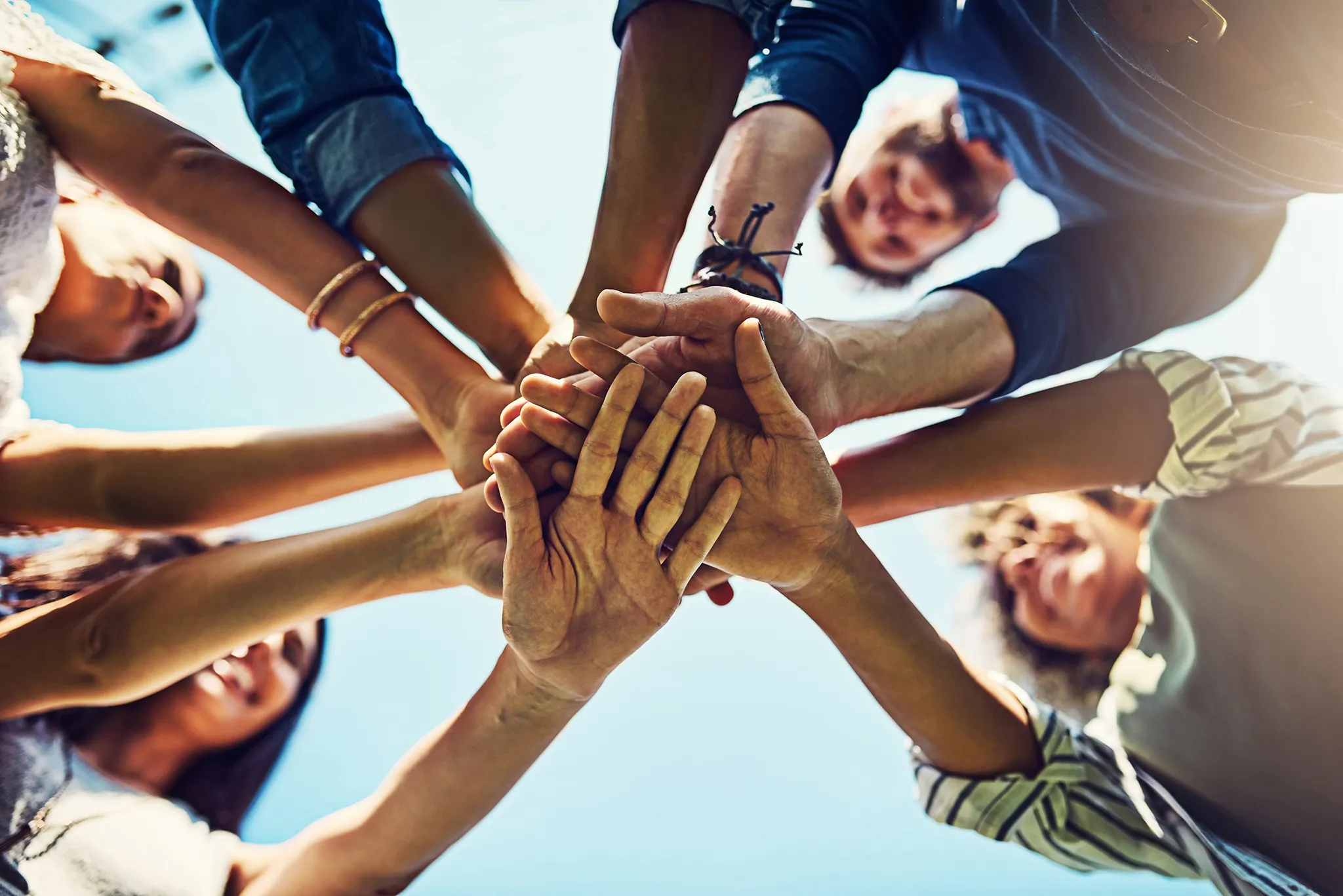 A group of people with hands piled to show a team supporting their community, next to text about PIB's community support initiatives