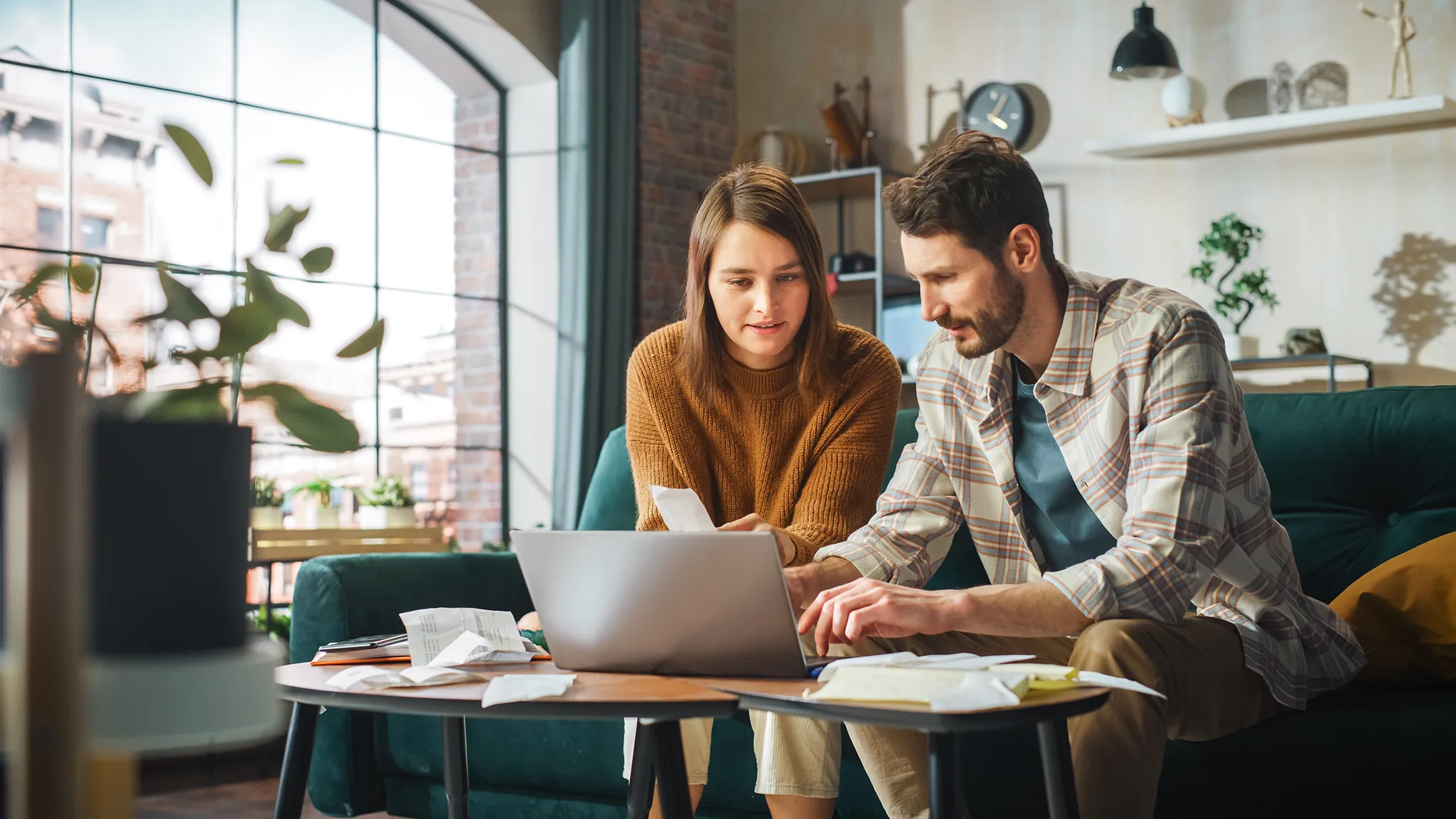 Young couple sitting on couch working on laptop