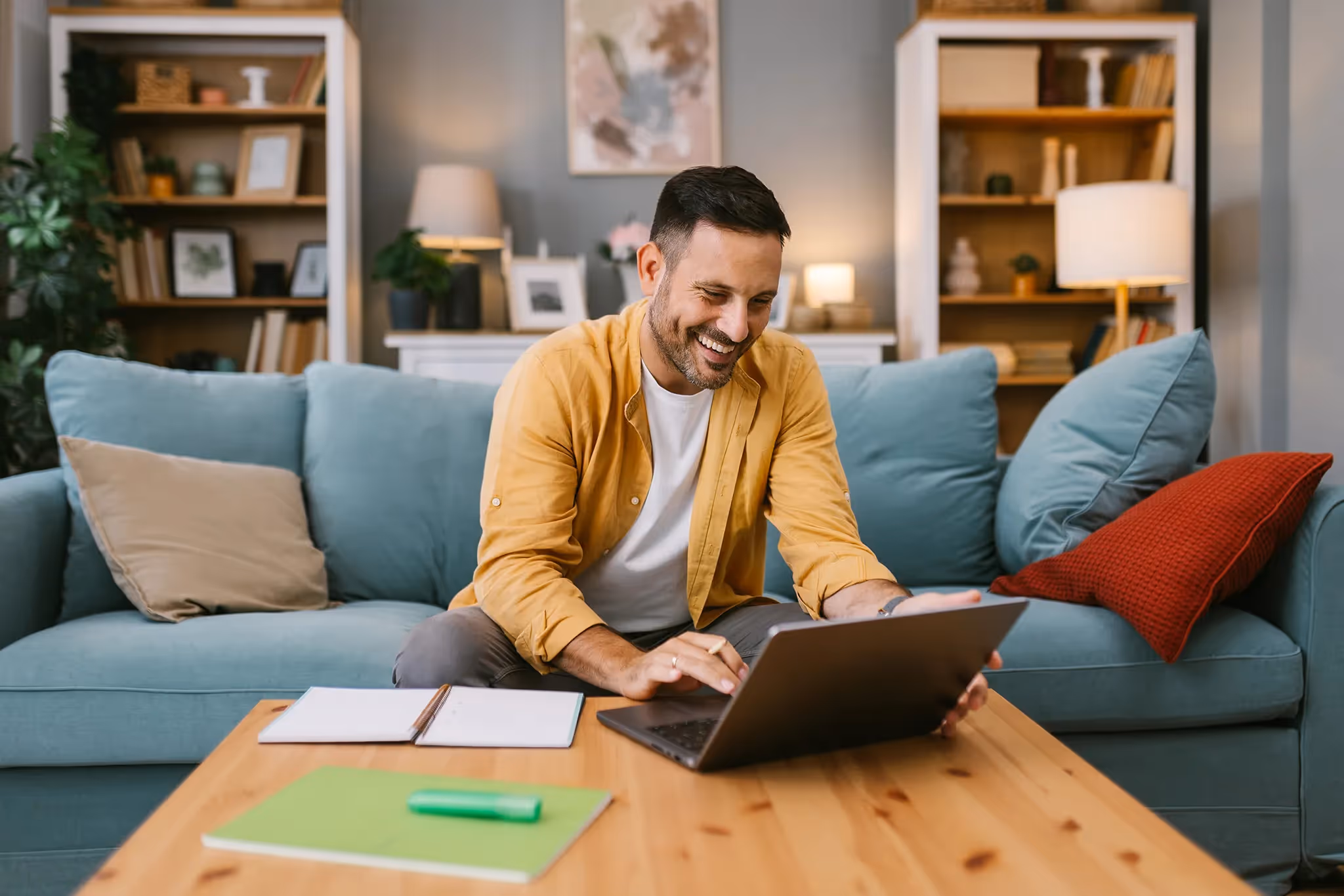 Middle-aged man smiling working on his computer in his living room