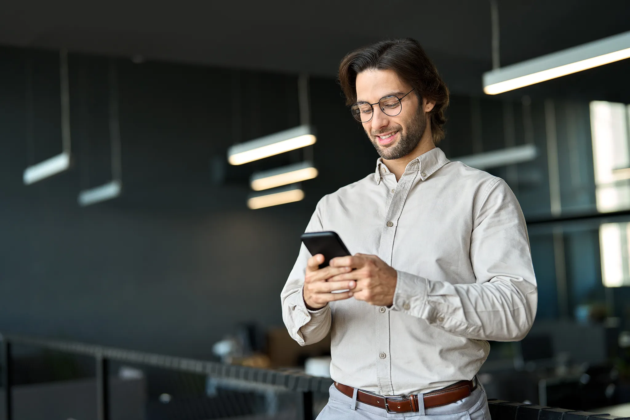 Young male business owner smiling while looking at his cellphone