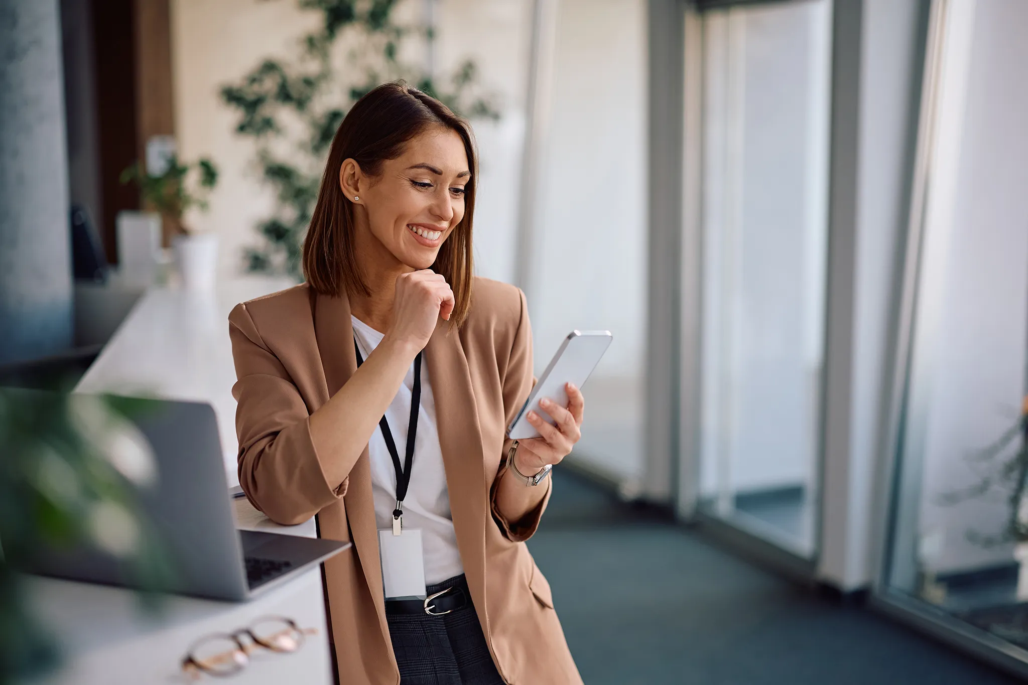 A middle-aged businesswoman smiling confidently looking at her tablet, happy knowing her employees are taken care of