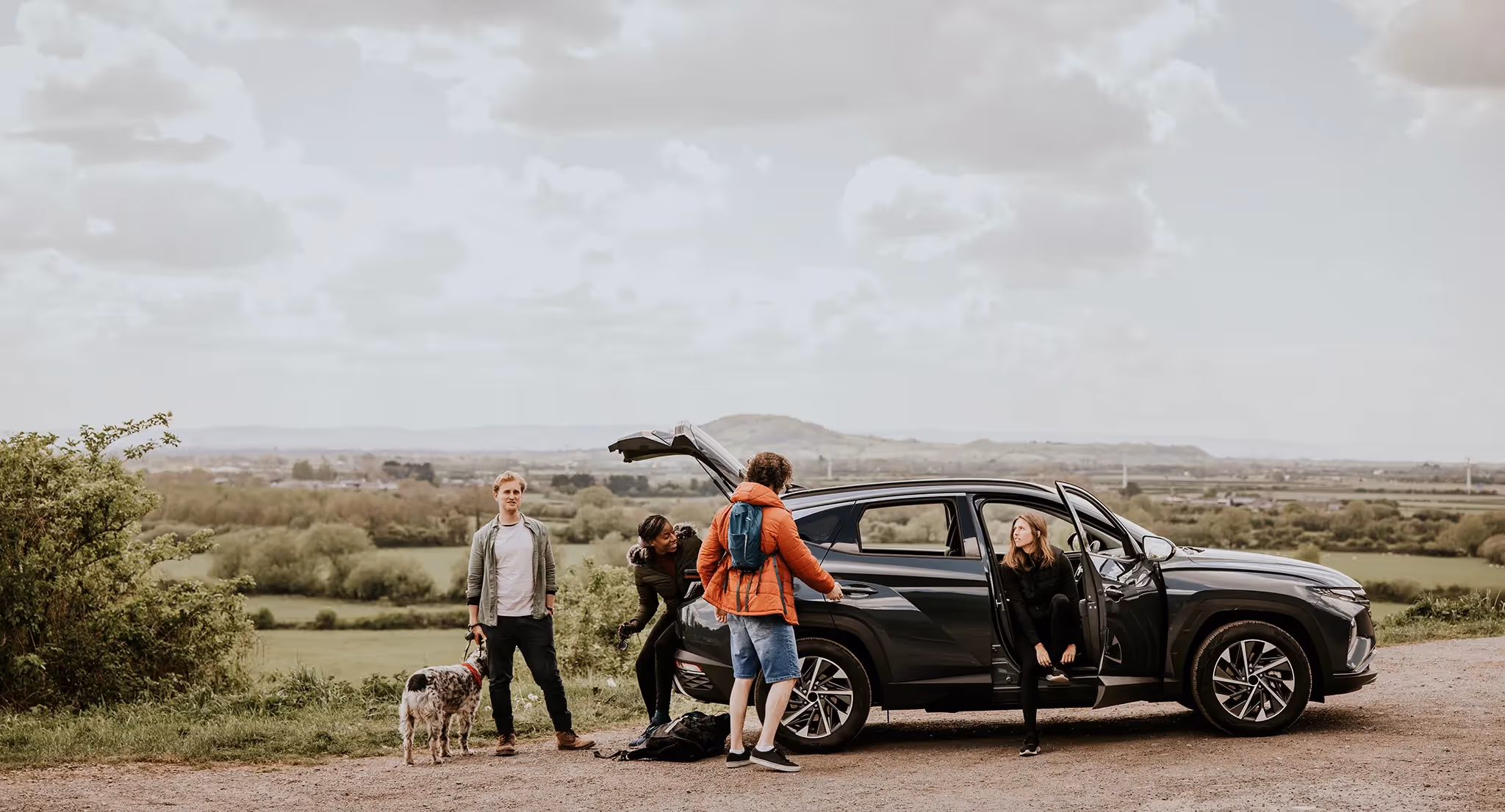Group of friends stopping and taking a break on the side of the road on a road trip