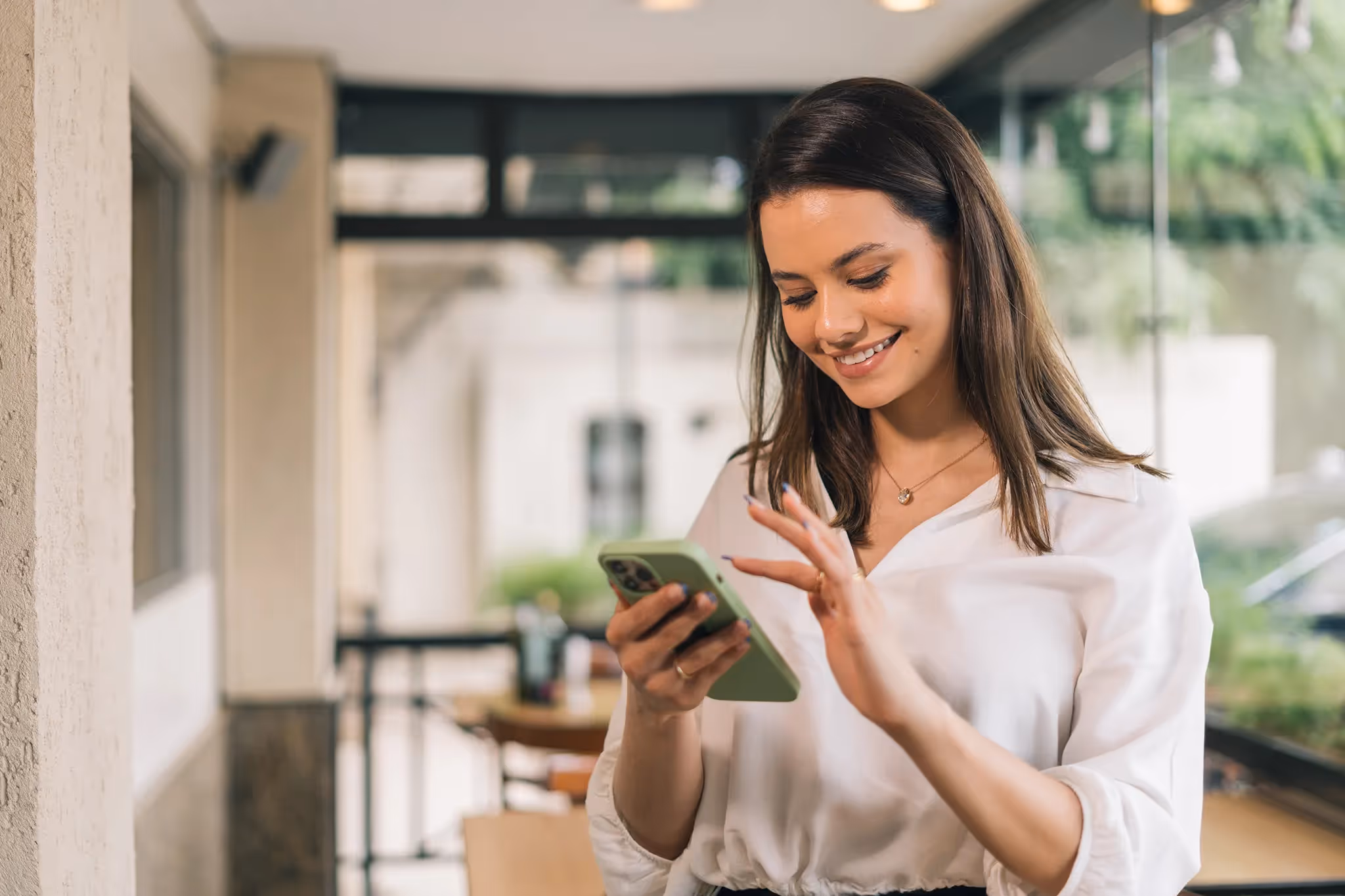 Young woman smiling while scrolling on her smartphone, confident that her financial future is secure