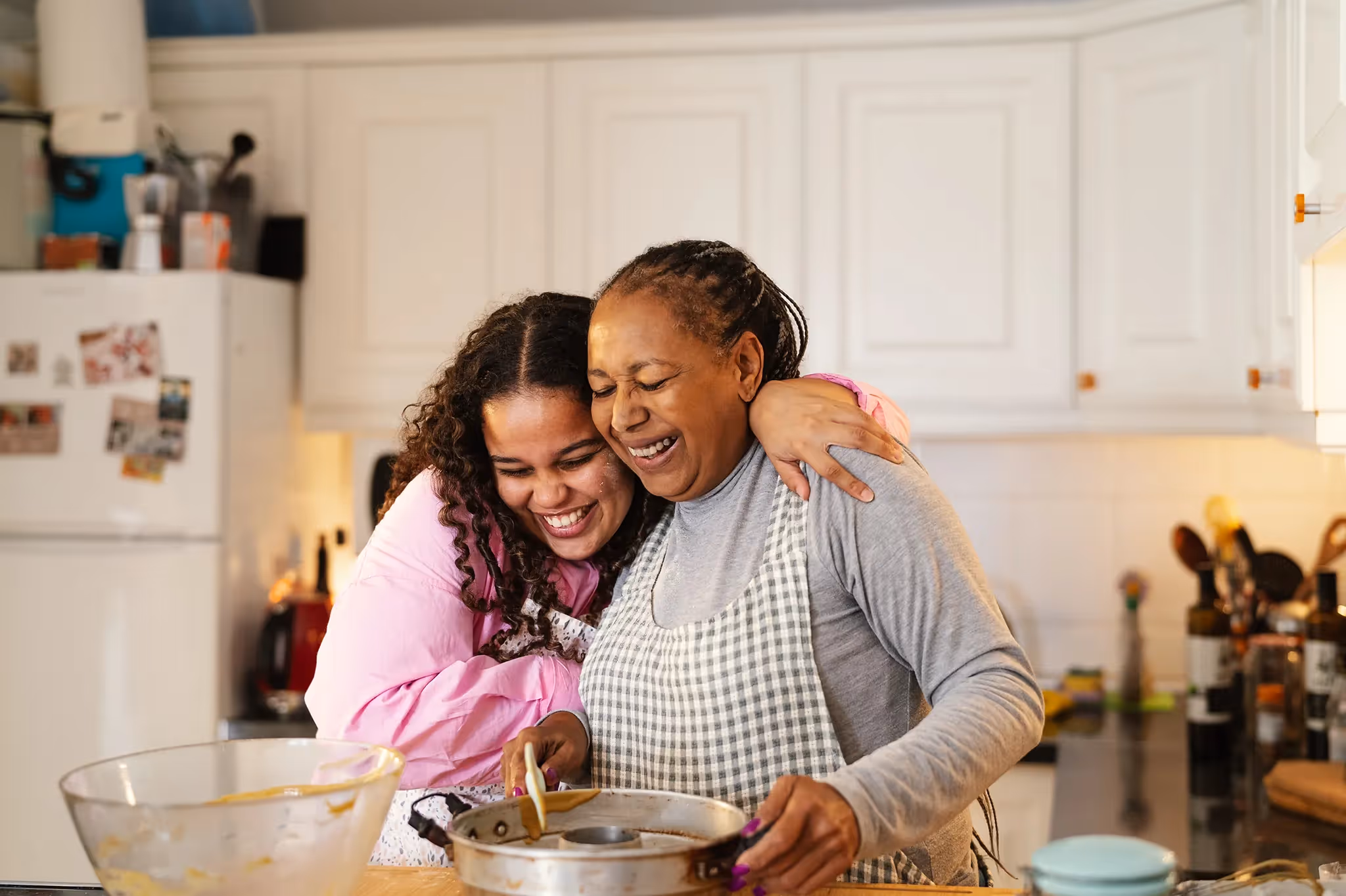 Grandmother and granddaughter baking together hugging alnd smiling