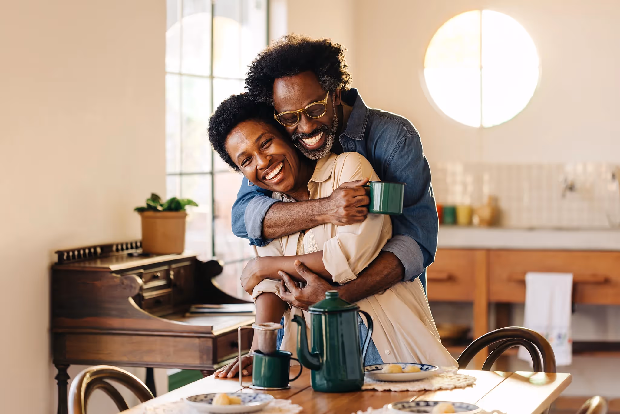 New homeowner couple hugging and laughing over a cup of coffee