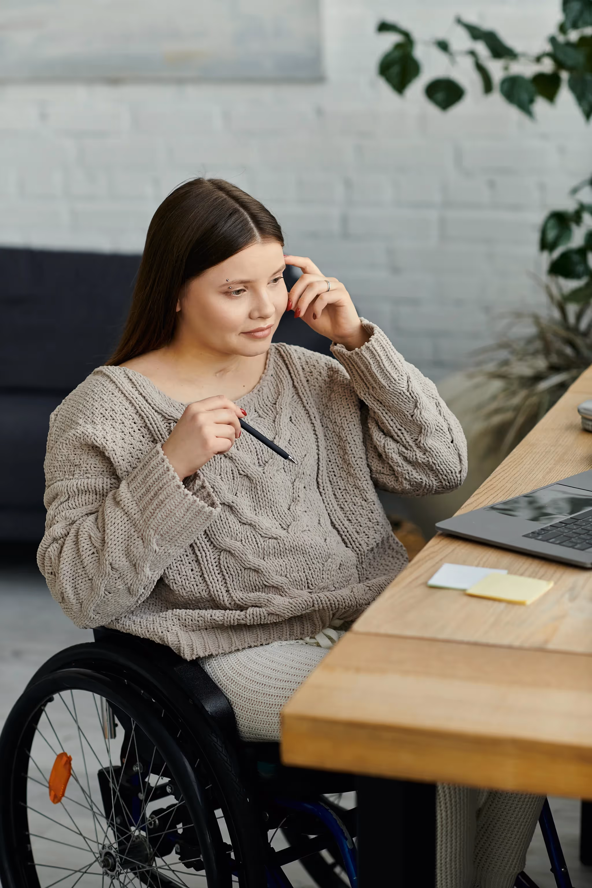 Young woman sitting in a wheelchair working on her laptop at her desk
