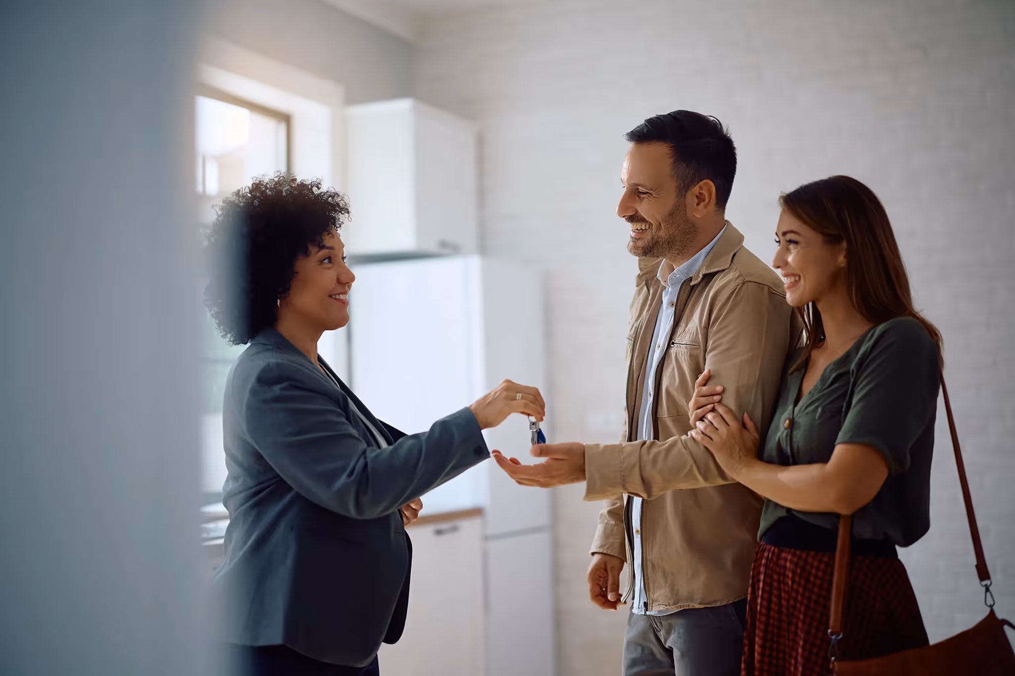 Landlord passing keys for apartment to new tenants excited to move in