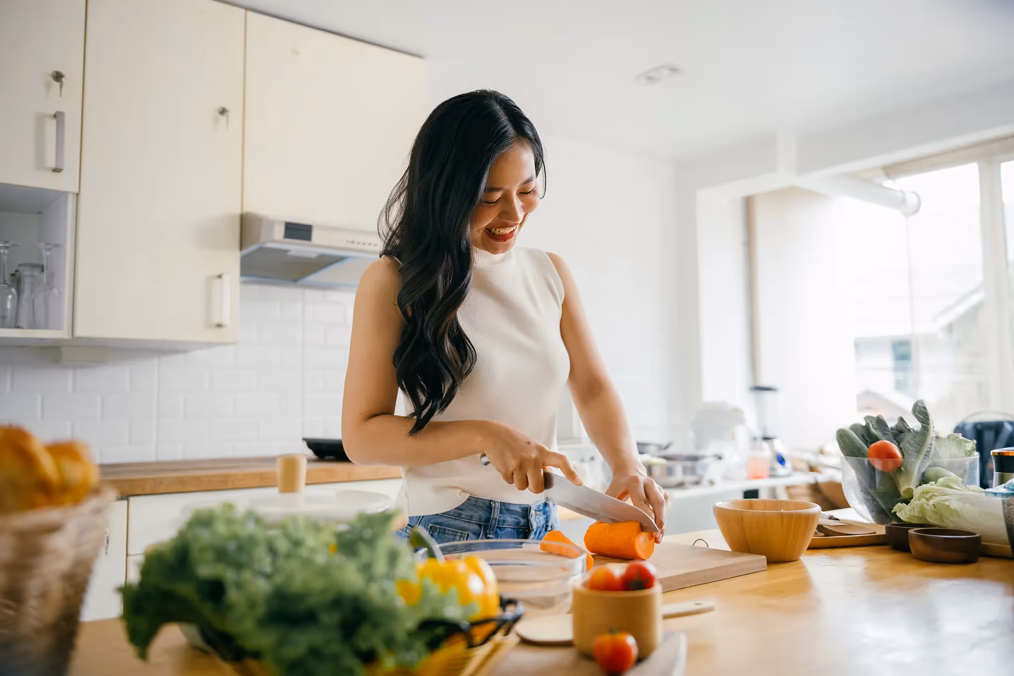 Young woman cutting vegetables for lunch in her condominium's kitchen 
