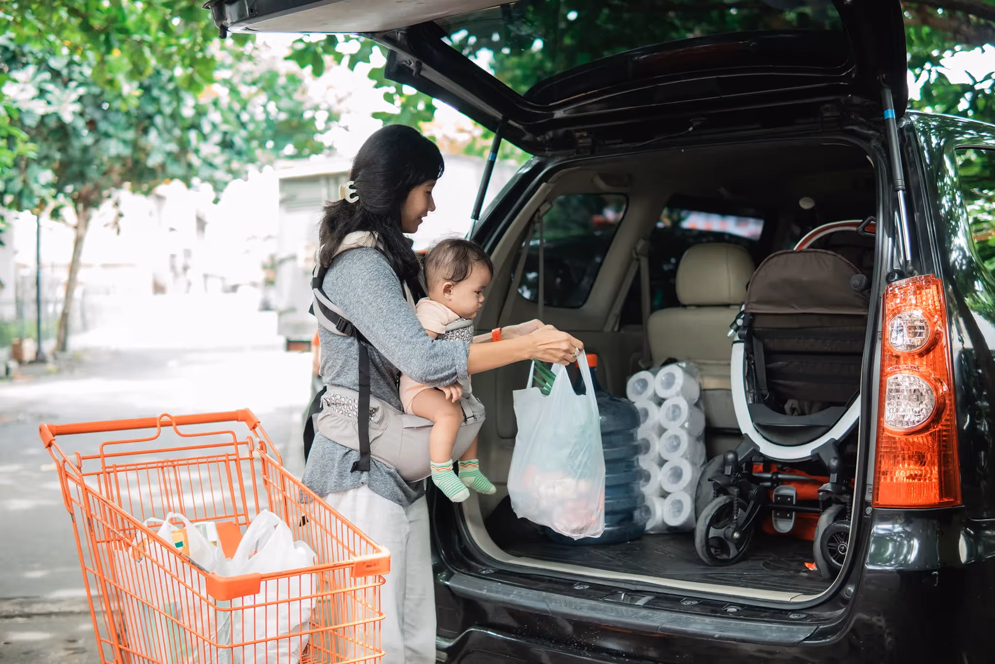 Mother with baby putting groceries in the back of a vehicle