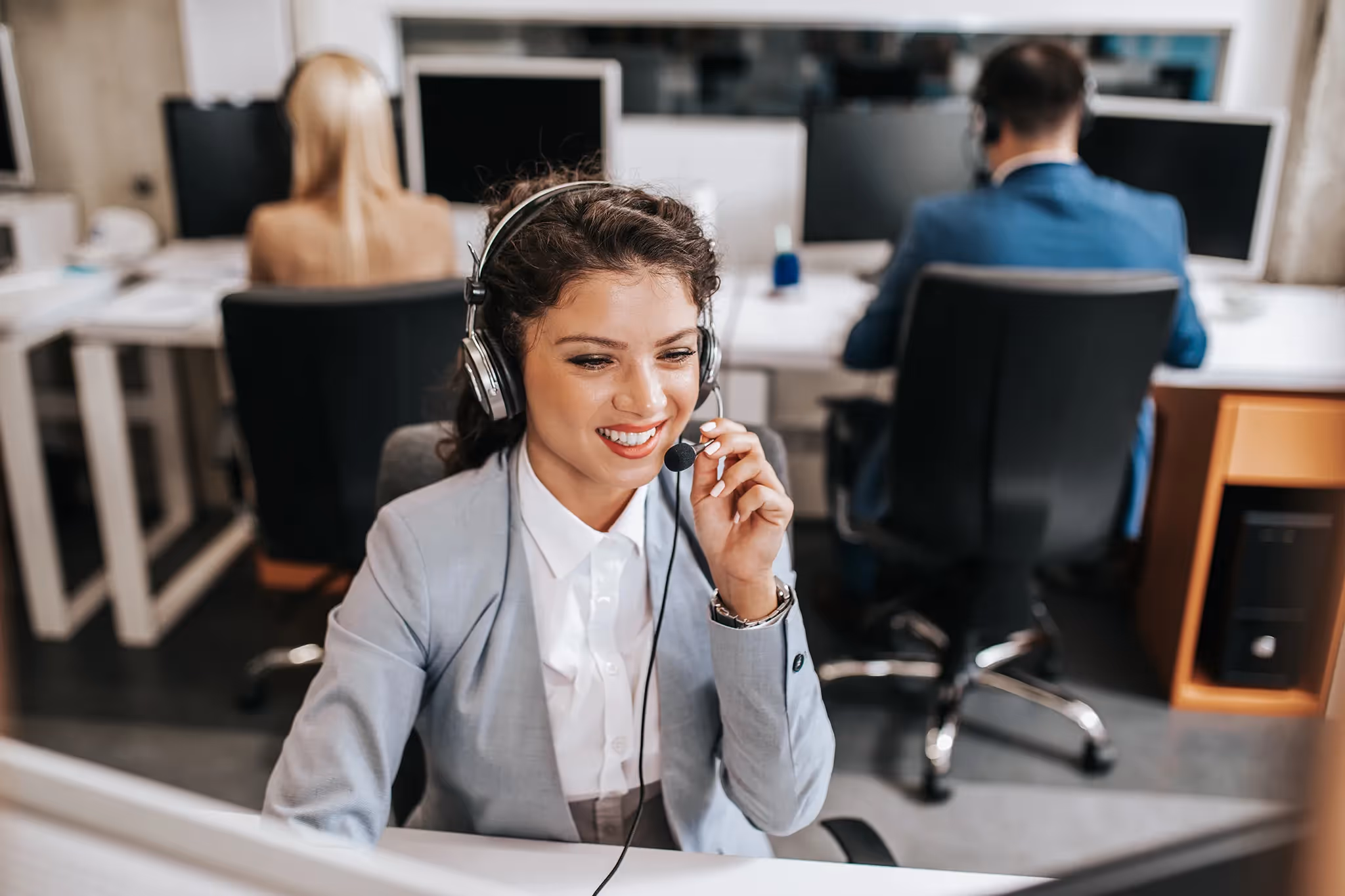 Young woman with headset at her desk in an office setting 