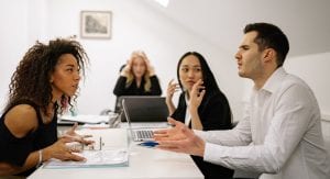 Four people arguing at a meeting table