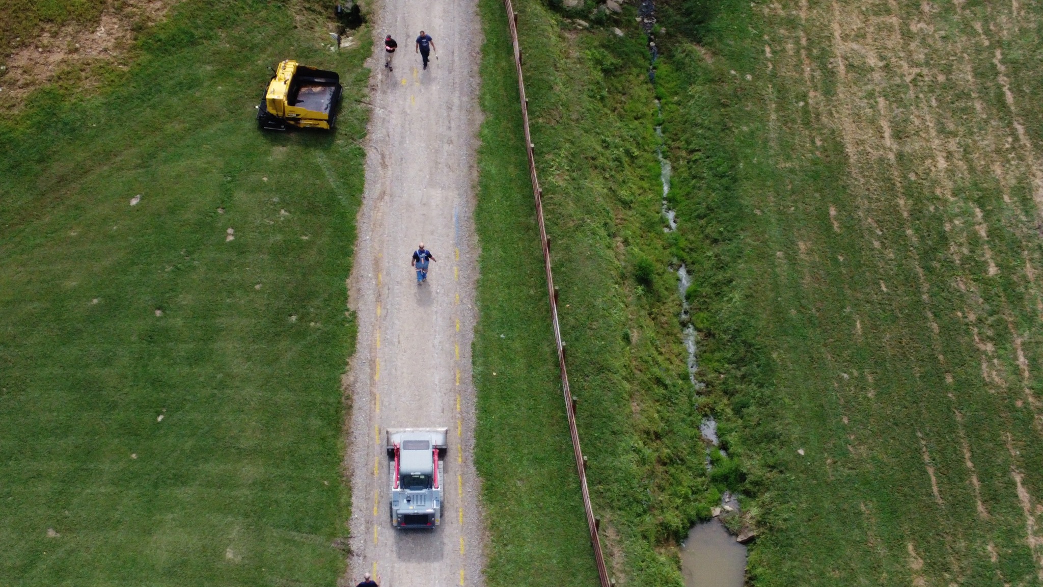 A road leading up to a farm that is being paved.