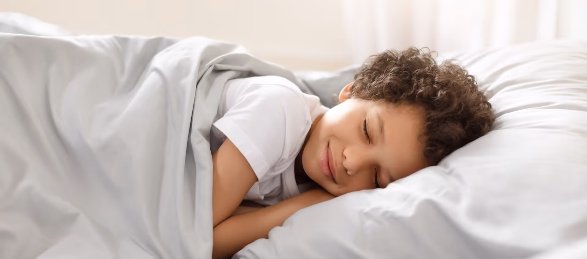 A 9 year old african american boy asleep in bed. Cozy