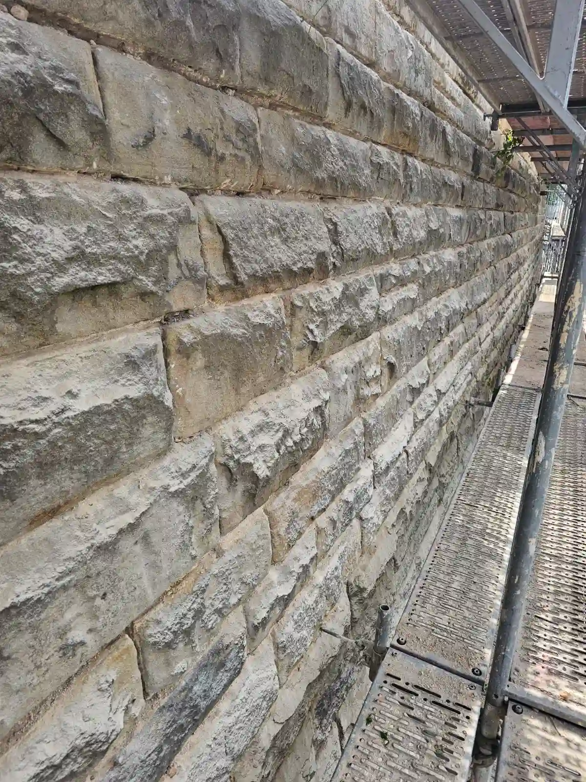 Seitlicher Blick auf eine hellgraue Wand aus Klinkersteinen