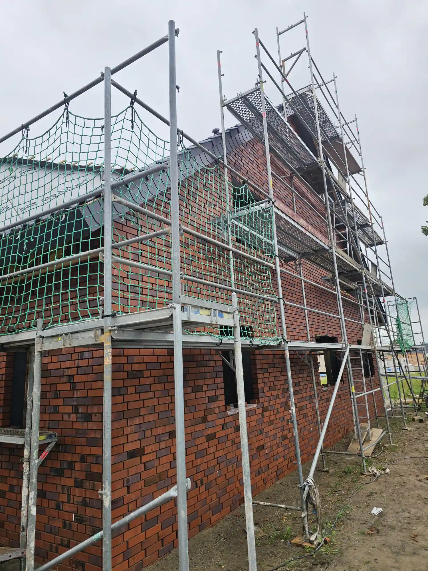 Haus mit roten Klinkerfugen und einem Baugerüst um das Gebäude