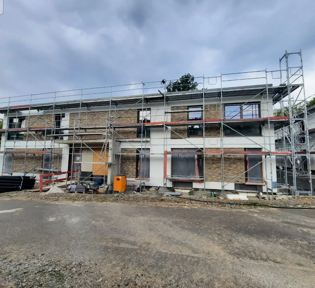 Haus mit weißer Wand, beigen Klinkersteinen und einem Baugerüst