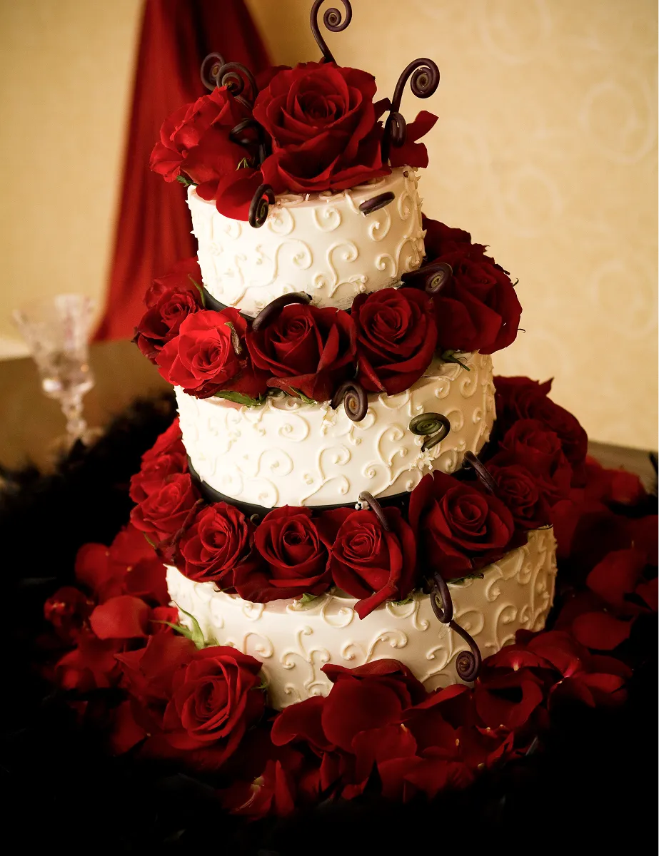 Three-tiered wedding cake with red roses and floral decorations at a Paradym Events wedding