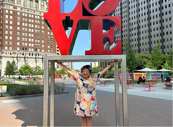 Mary from Paradym Events standing under a large red LOVE sculpture during an event setup
