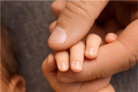 Father gently holding his newborn child’s tiny hand