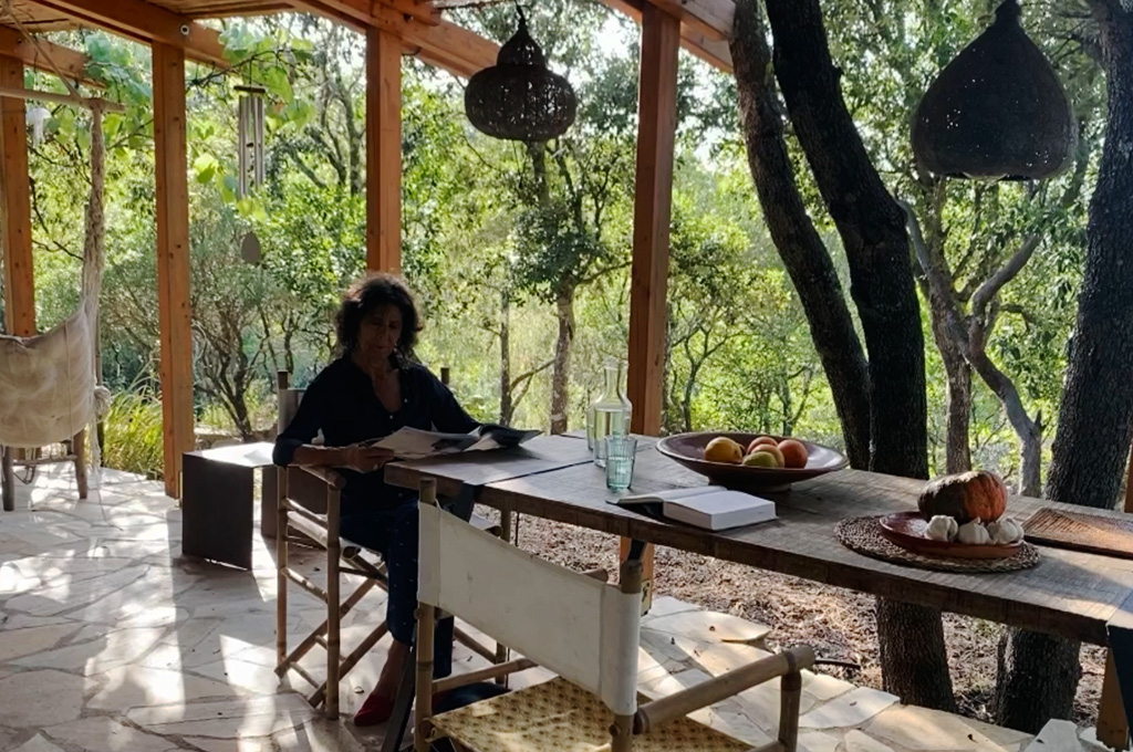 Outdoor shower area with bamboo walls and wooden roof surrounded by greenery and trees