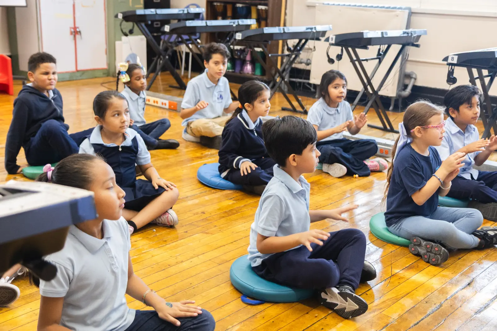 Students sitting on floor in music classroom with keyboards